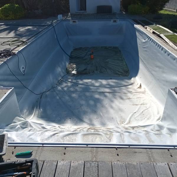 Détail de la pose du liner gris clair sur cette piscine avec escalier en bout, une rénovation soignée et durable