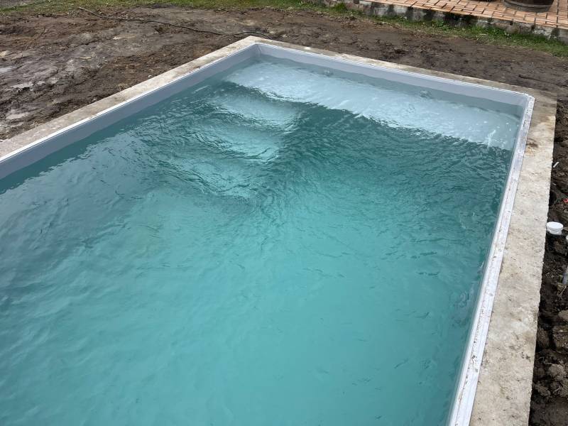 Construction d’une piscine traditionnelle en parpaing à Mérignac, bassin compact de 4x2,5 m avec fond plat, idéale pour profiter d’un espace baignade dans un jardin optimisé.