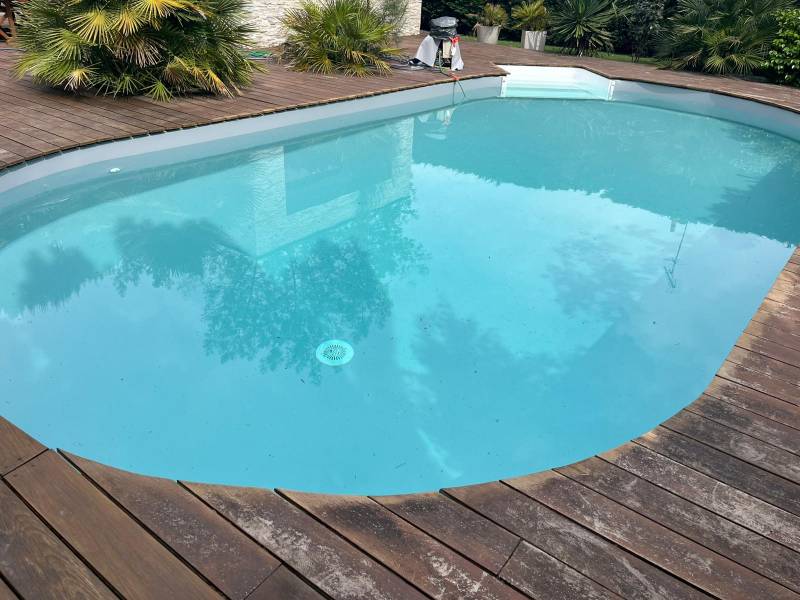 Rénovation de piscine forme libre en Gironde : changement de liner gris clair pour un rendu moderne et élégant.